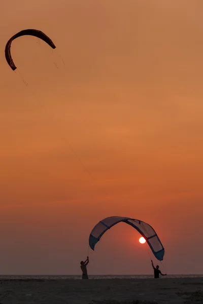 Auringonlaskun aikaan purjehtivien leijalautailijoiden siluetti — kuvapankkivalokuva