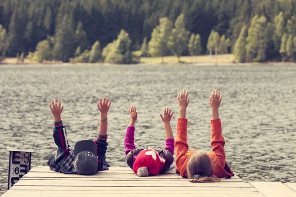 Color image of three children siting on pontoon on lake — Stock Photo, Image