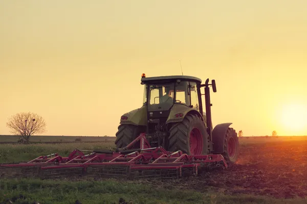 Трактор на закате занимается сельским хозяйством Стоковое Изображение