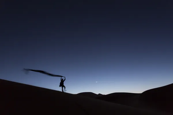 Homem andando sobre dunas no deserto à noite — Fotografia de Stock