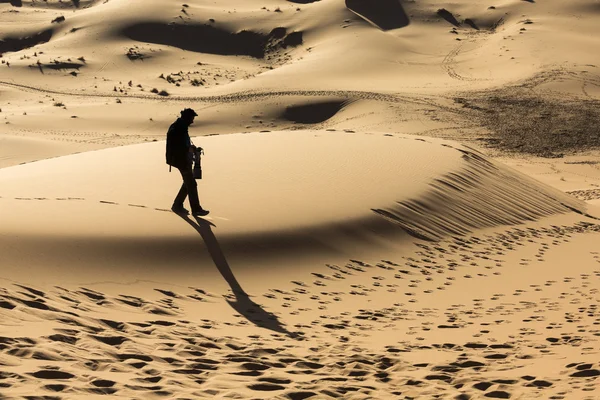 Homem caminhando sobre dunas no deserto — Fotografia de Stock