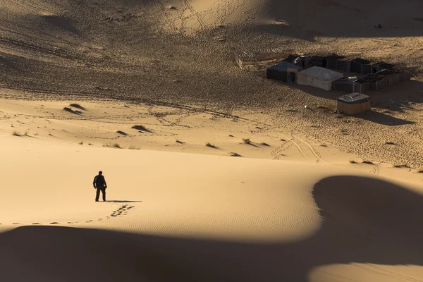Человек ходит по дюнам в пустыне — стоковое фото
