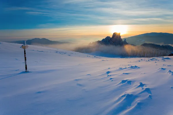 Metall skylt i snö på berg i solnedgång — Stockfoto