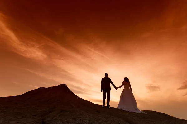 Silhouette des Hochzeitspaares mit dem roten Sonnenuntergang — Stockfoto