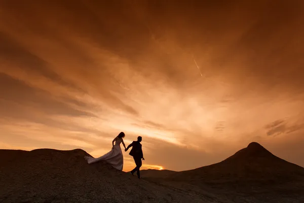 Silhouette des Hochzeitspaares mit dem roten Sonnenuntergang — Stockfoto