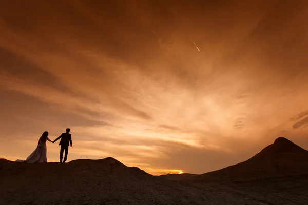 Silhouette des Hochzeitspaares mit dem roten Sonnenuntergang — Stockfoto