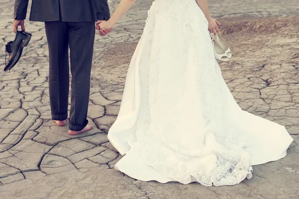 Bruidspaar houden op prullenmand de jurk met vuile jurk — Stockfoto