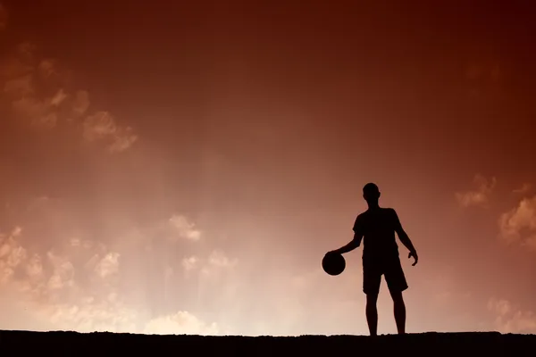Silhouette of man playing basketball