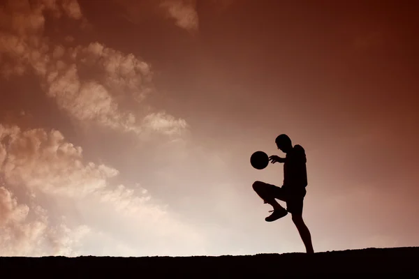 Silhouette eines Fußballmannes, der mit dem Ball spielt — Stockfoto