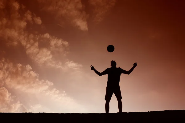 Silhouette eines Fußballmannes, der mit dem Ball spielt — Stockfoto