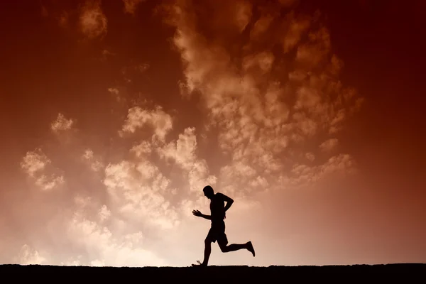 Silhouette of sport man running with blue sky and clouds on back — Stock Photo, Image