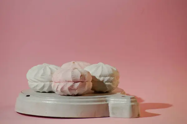 Pink and white marshmallows on a bright pink background