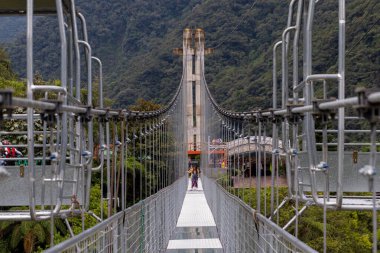 Banos De Agua Santa, Ekvador - 16 Ocak 2022: Mega Park 'ta çekim. Turistler, 'Puente de Cristal' adı verilen asma kablo köprüsünden derin bir kanyonun üzerinde yürüyorlar. 