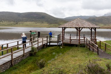 Cotopaxi, Ekvador - 19 Mart 2022: Gözlem güvertesinde bir grup turist ve bulutlu bir günde Cotopaxi Ulusal Parkı 'ndaki Limpiopungo Gölü' nde ahşap yürüyüş. Cotopaxi ili, Ekvador