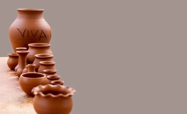 Master class on modeling on a pottery wheel. A few example of raw ceramic jars, vases and pots out of clay. The sign \'Viva\' or \'Long life\