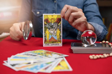 Bangkok, THAILAND - Ekim 04, 2021: Falcı Tarot servetini elinde tutuyor Masadaki en popüler tarotlardan birinin sevgililer kartı.