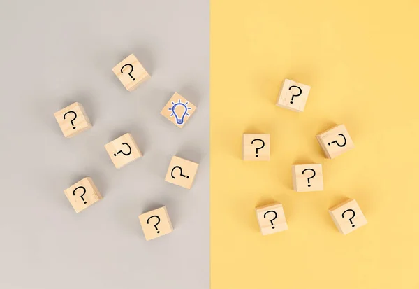 Concept to find idea in problem solving for business.  Wooden cube question mark and light bulb icons