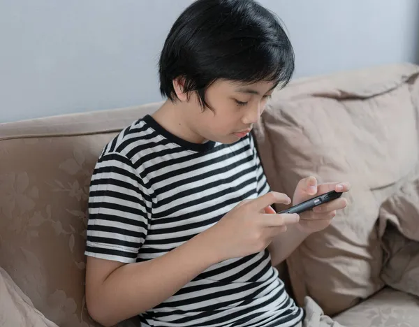 Çocuk evde akıllı telefondan oyun oynuyor. Teknoloji ve rahatlama zamanı