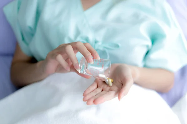 病院で病気を治療するために錠剤を服用する手 — ストック写真