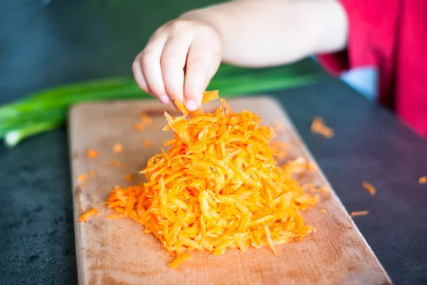 Child taking grated carrots — Stock Photo, Image