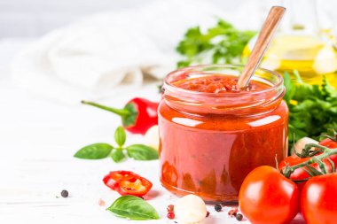 Beyaz arka planda otlu domates sosu ve baharatlar.