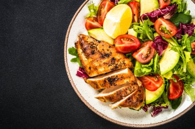 Ahşap masada taze salata ve ızgara tavuk..