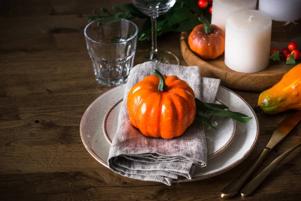 Jesienny stół z talerzem, dynią i świecami. — Zdjęcie stockowe