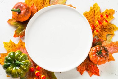 Sonbahar sofrası beyaz tabak, altın çatal bıçak ve sonbahar süslemeleri..