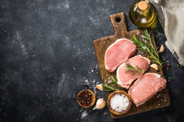 Tahtada taze domuz bifteği ve yemek malzemeleri var..