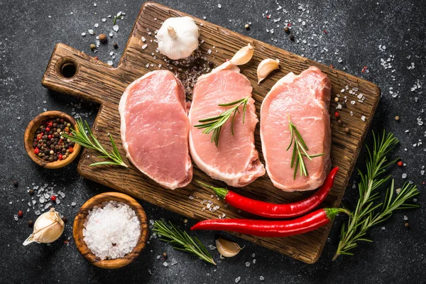 Filetes de cerdo frescos en la tabla de cortar con ingredientes para cocinar. —  Fotos de Stock