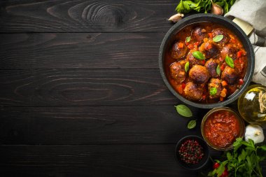 Koyu ahşap masada tavada domates soslu köfte..