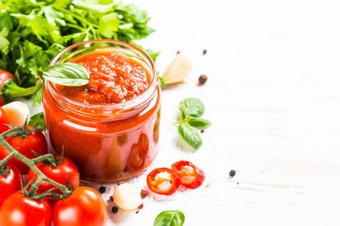 Beyaz arka planda otlu domates sosu ve baharatlar.