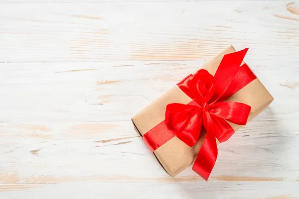 Caja de regalo con cinta roja en mesa blanca. — Foto de Stock