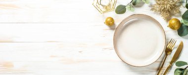 Noel sofrasında okaliptüs yaprakları ve altın süslemeler.