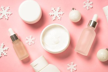 Kış kozmetik ürünleri, pembe arka planda cilt bakım ürünleri.