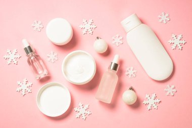 Kış kozmetik ürünleri, pembe arka planda cilt bakım ürünleri.