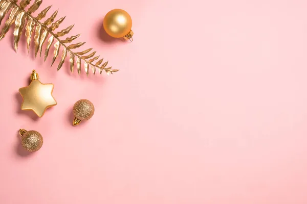 Vánoční kompozice se zlatými vánočními ozdoby na růžovém pozadí. — Stock fotografie
