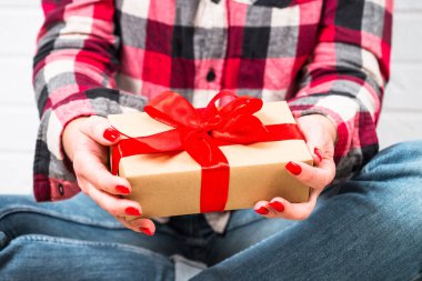 Kadın Noel hediyesini kırmızı kurdeleli kutuda tutuyor..