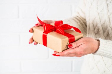 Kadın Noel hediyesini kırmızı kurdeleli kutuda tutuyor..