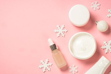 Kış kozmetik ürünleri, pembe arka planda cilt bakım ürünleri.