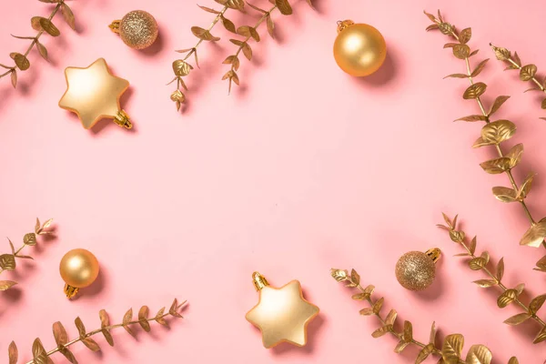 Vánoční kompozice se zlatými vánočními ozdoby na růžovém pozadí. — Stock fotografie