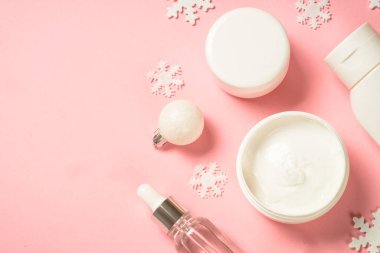 Kış kozmetik ürünleri, pembe arka planda cilt bakım ürünleri.