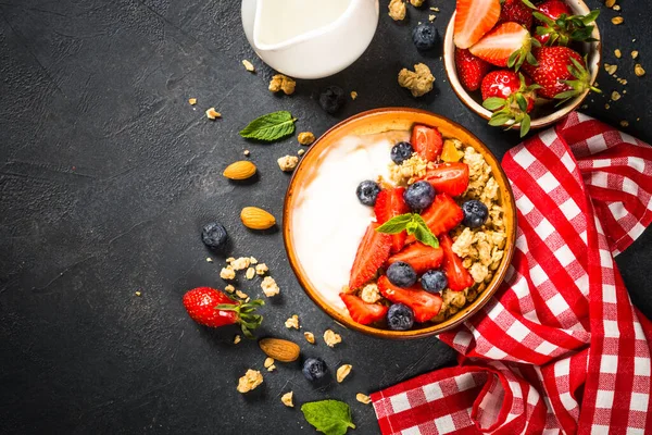 Grecki jogurt granola ze świeżymi jagodami na czarnym kamiennym stole. — Zdjęcie stockowe