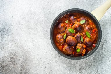 Domates soslu köfte ve hafif taş masada fesleğen..