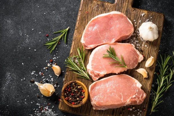 Fresh pork steaks on cutting board with ingredients for cooking. — Stock Photo, Image