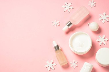 Kış kozmetik ürünleri, pembe arka planda cilt bakım ürünleri.