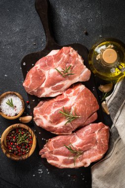 Siyah arka planda baharatlı ve otlu taze biftekler.
