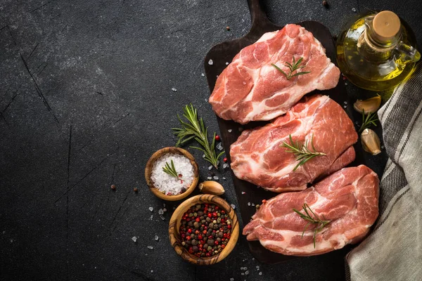 Fresh steaks with herbs and spices at black background. — Stock Photo, Image