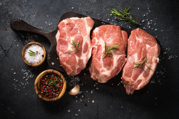 Fresh steaks with herbs and spices at black background. — Stock Photo, Image