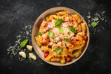 İtalyan makarnası alla arrabiata fesleğen ve parmesan peyniri ile koyu masa..